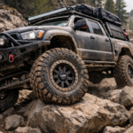 A heavily modified overland 4x4 truck navigating a brutal rocky trail, equipped with durable CNWR custom forged beadlock wheels designed for extreme off-road terrain.