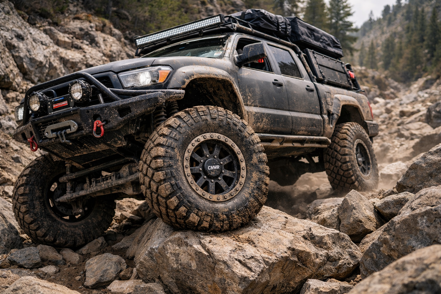A heavily modified overland 4x4 truck navigating a brutal rocky trail, equipped with durable CNWR custom forged beadlock wheels designed for extreme off-road terrain.